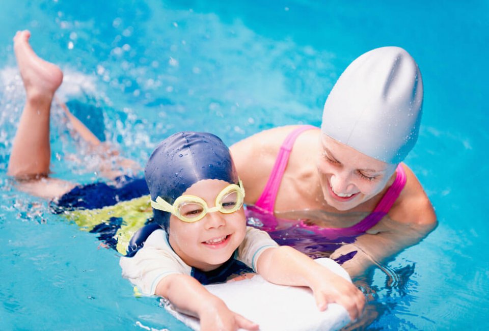 Trainer giving swim lessons to young swimmer
